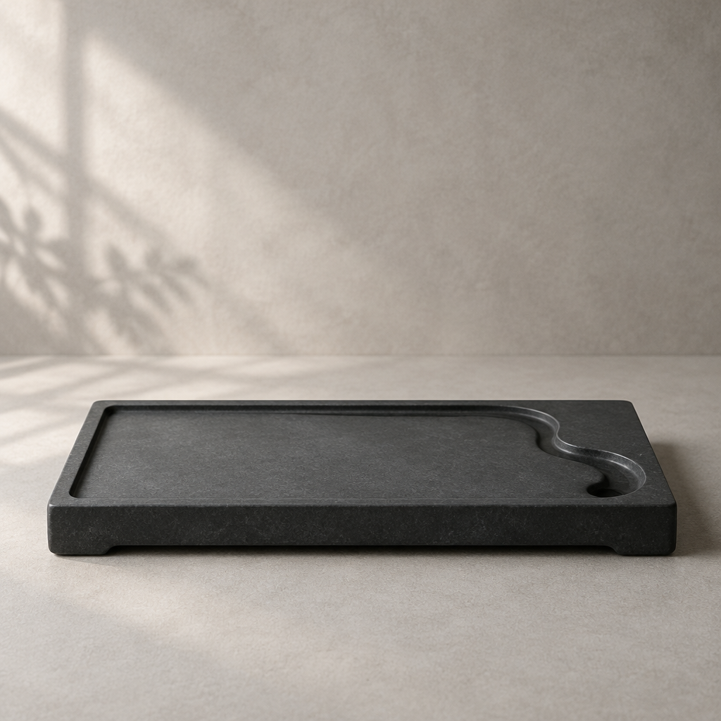 A flat dark inkstone tea tray with a subtle carved water channel on a pale background.